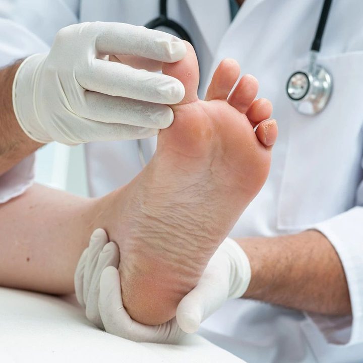 A doctor is examining the foot of a patient.