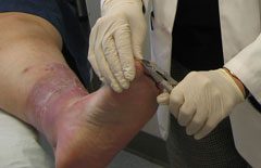 A person is cutting another persons foot.